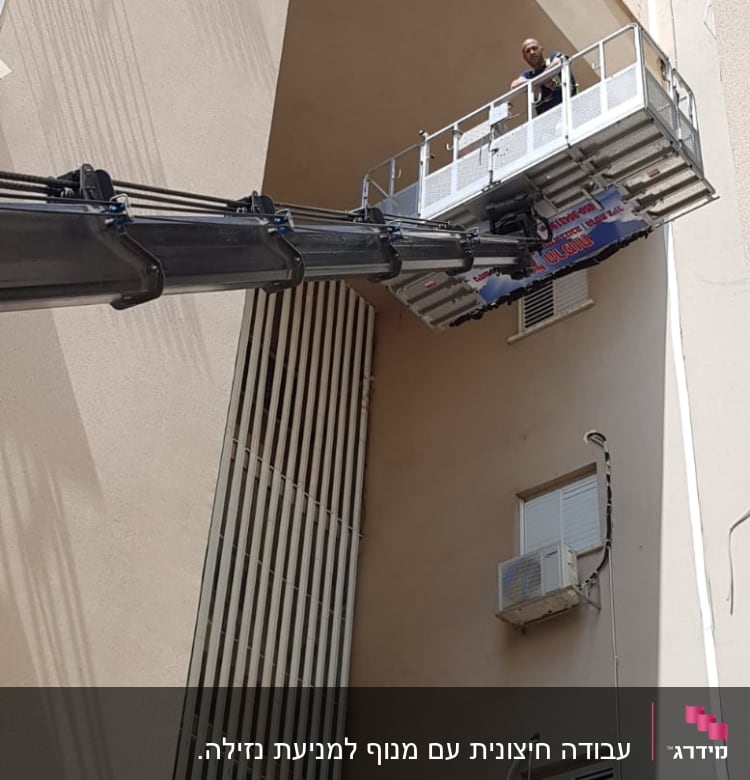 פיגום הרמה עם אדם בעבודה על קיר חיצוני